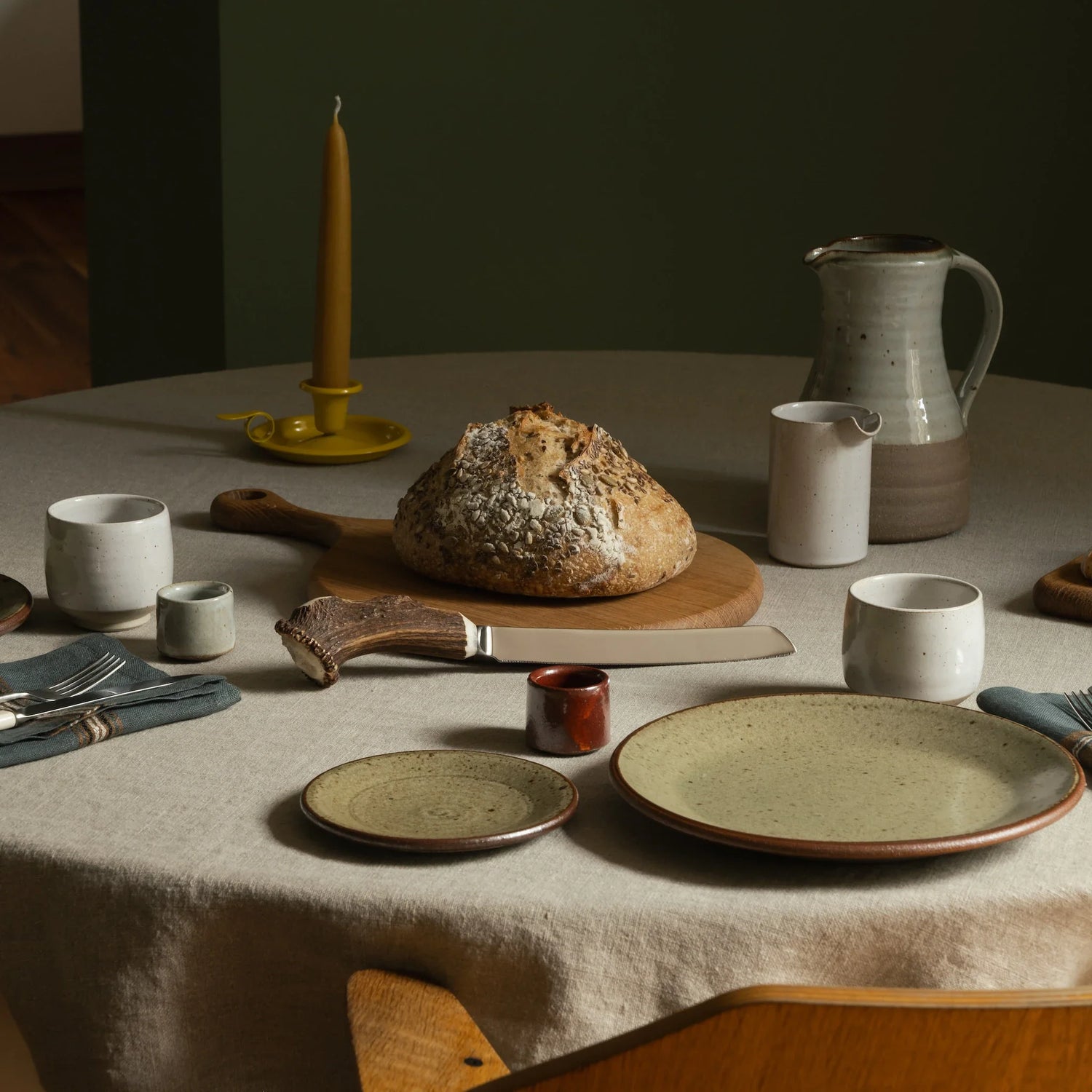 Table with Leach Pottery plates, Pottery West beakers, Selwyn House board and assorted cutlery