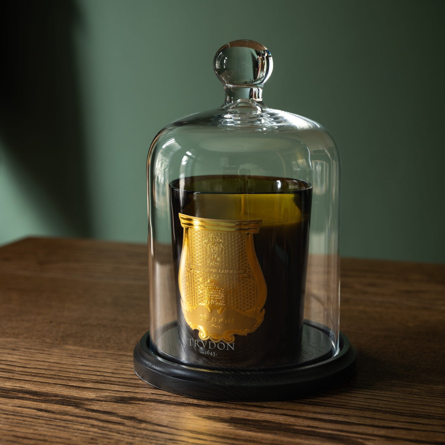 Trudon scented candle in glass cloche on a wooden base