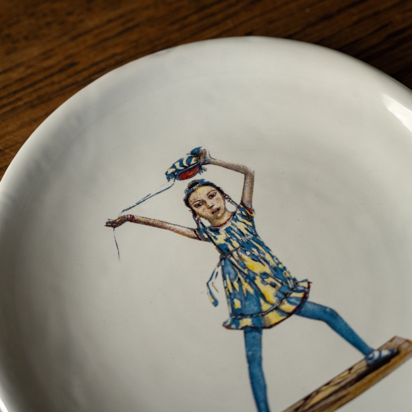 Close up of Carron Paris ceramic plate with an illustrated design of a dancing woman in a blue and yellow dress