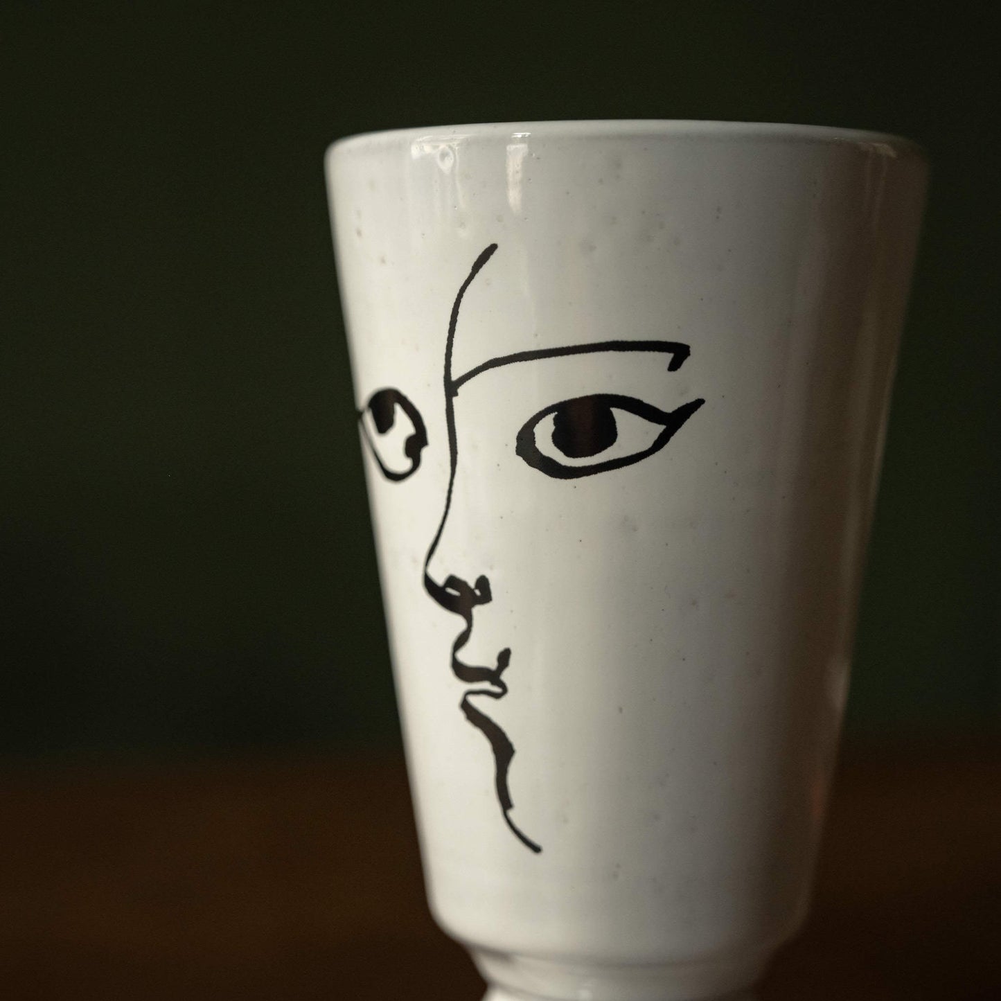Close-up of Carron Paris small white ceramic vase with black line art of a face