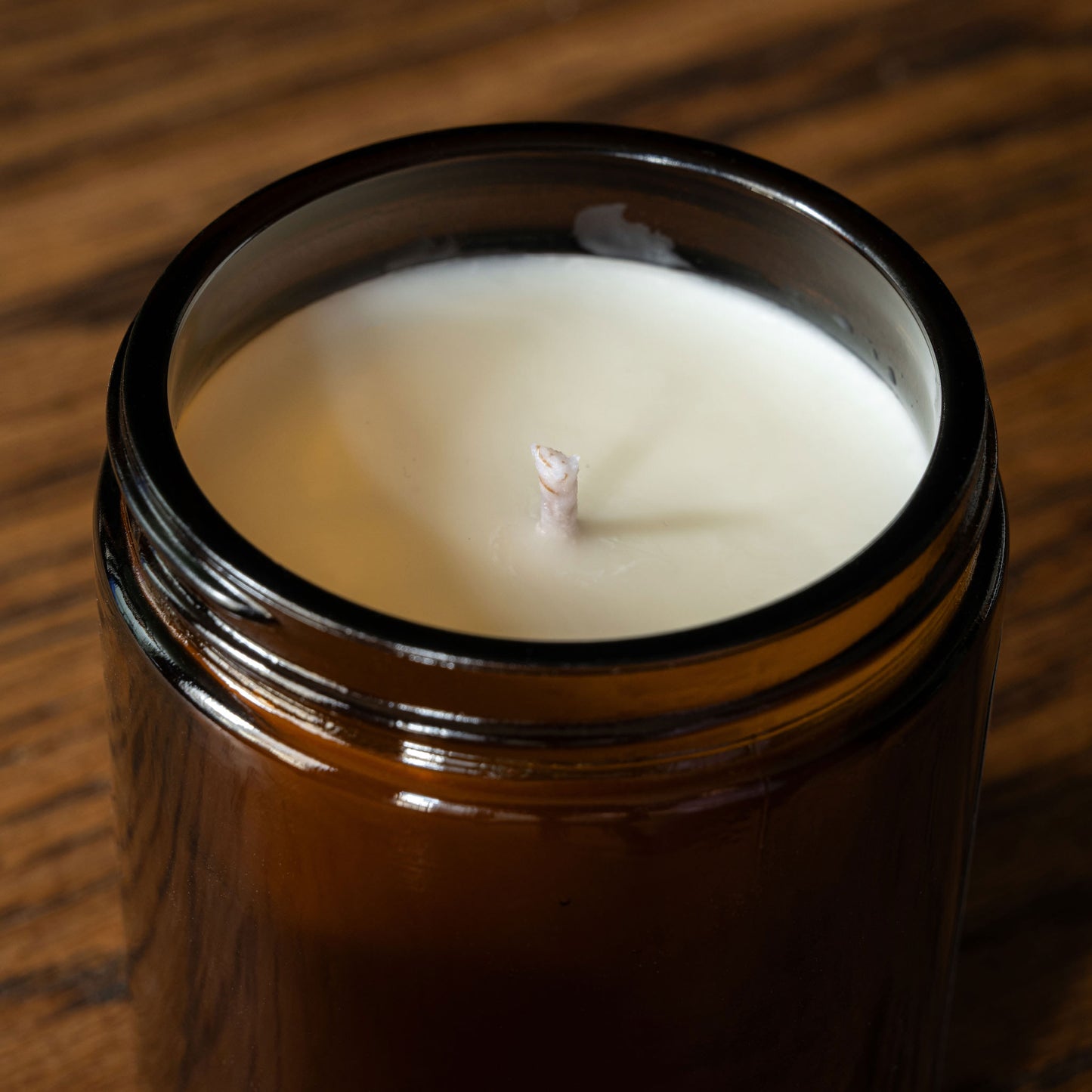 Close up of Charlotte Spencer candle wick in a glass jar with a wooden background