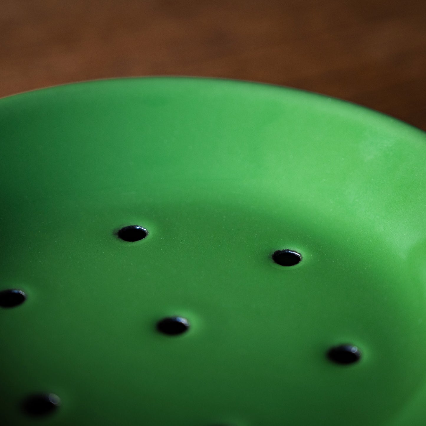 Close-up of green enamel soap dish draining holes