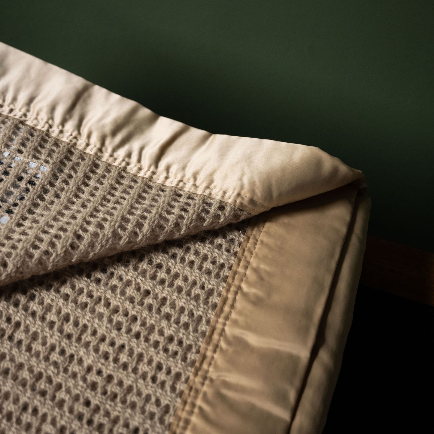 Satin binding of John Atkinson Atkincel Cellular Blanket in camel colour.