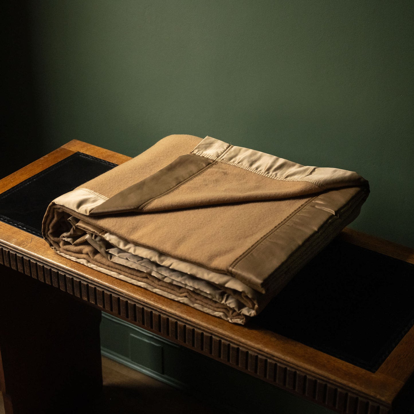 John Atkinson Duchess Merino Wool Blanket with Satin Binding in Champagne colour, folded on table.