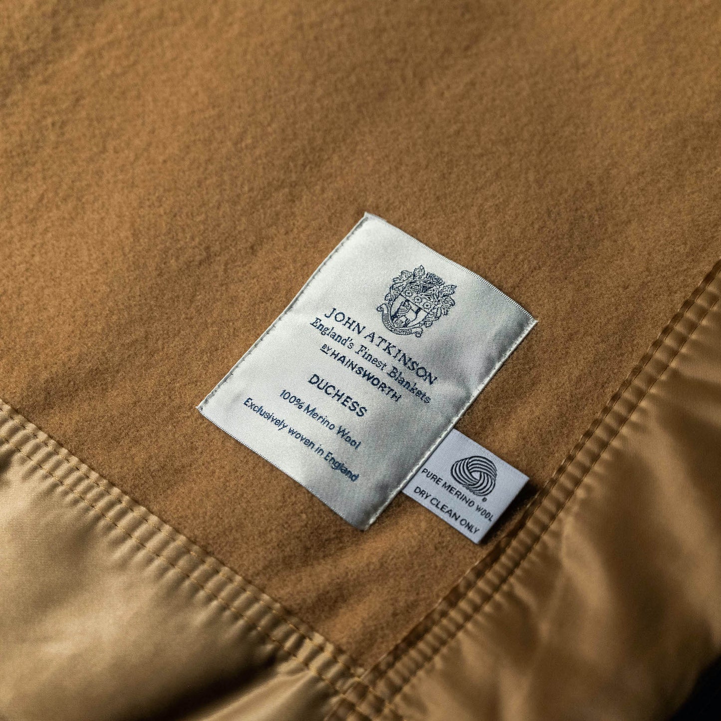 label & care instructions for John Atkinson Duchess Merino Wool Blanket with Satin Binding in Champagne colour.