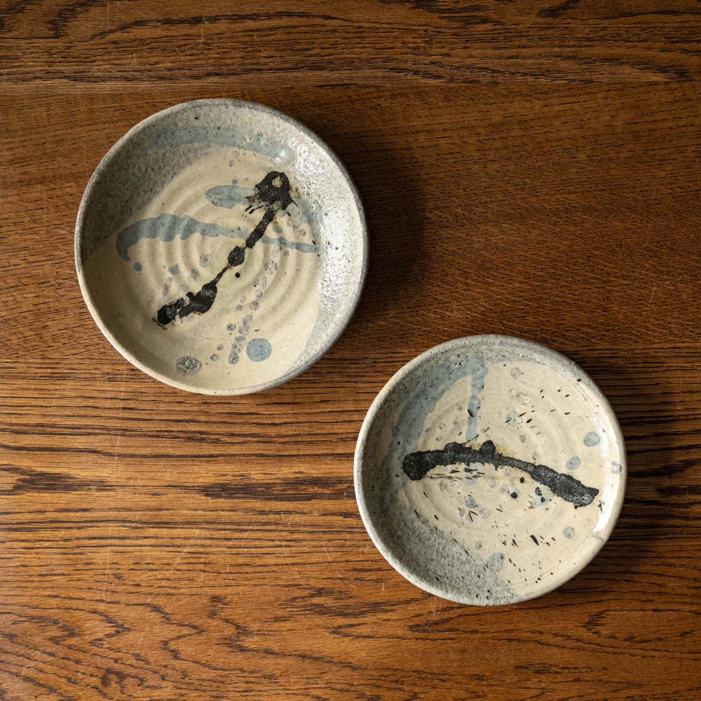 Two Joshua Williams earthenware plates with unique slip designs on a cream base glaze