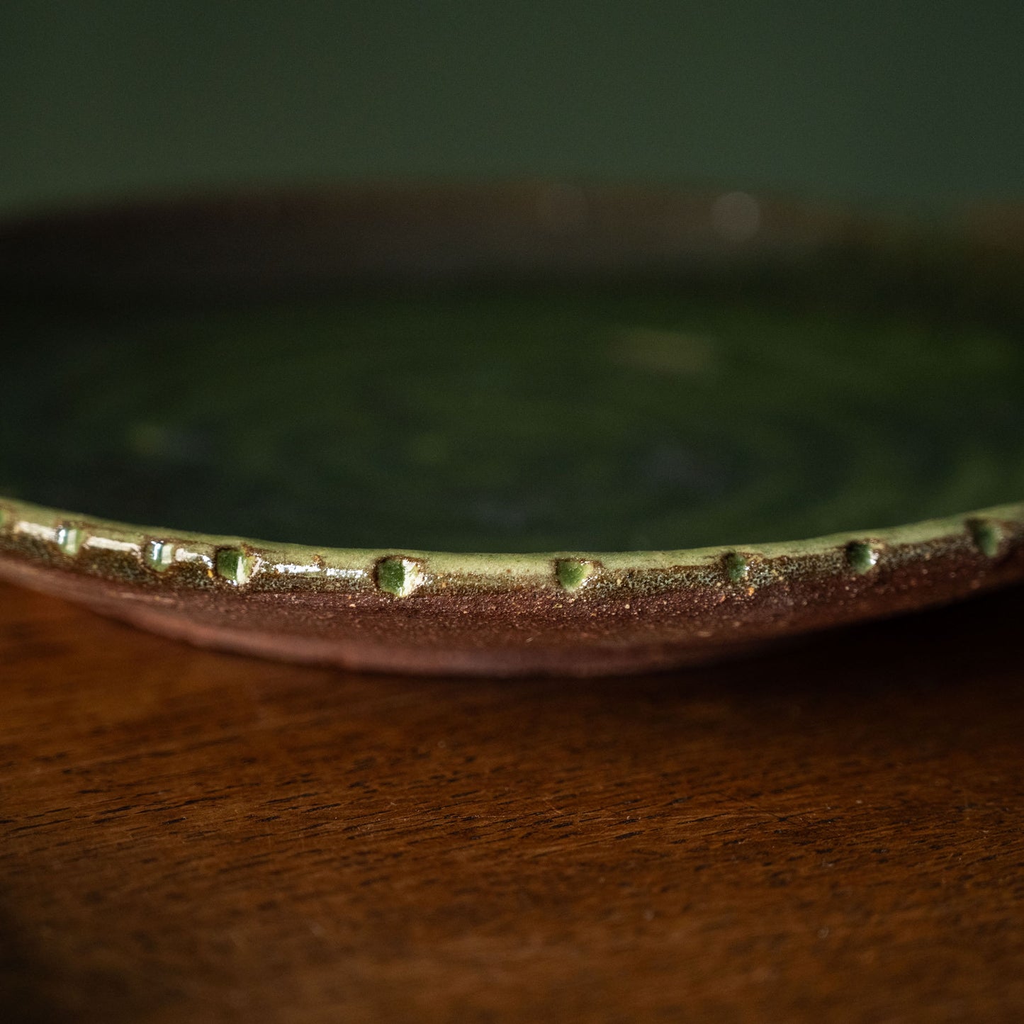 Close-up of Joshua Williams earthenware plate with green glazed finish