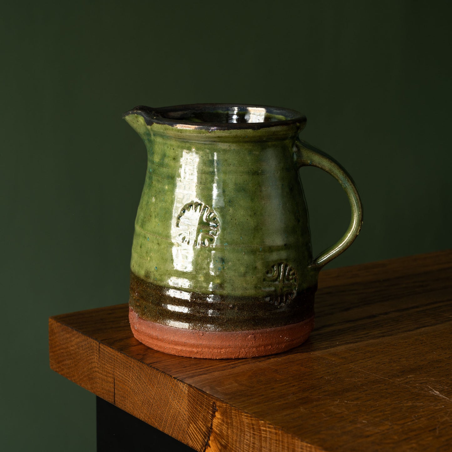 Joshua Williams green earthenware jug on a wooden surface