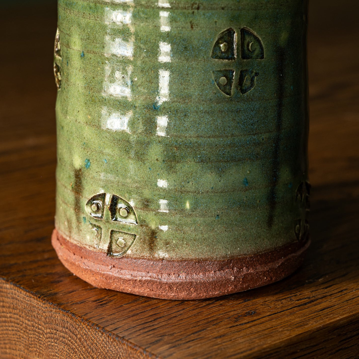 Close-up of Joshua Williams green earthenware mug with decorative surface patterns