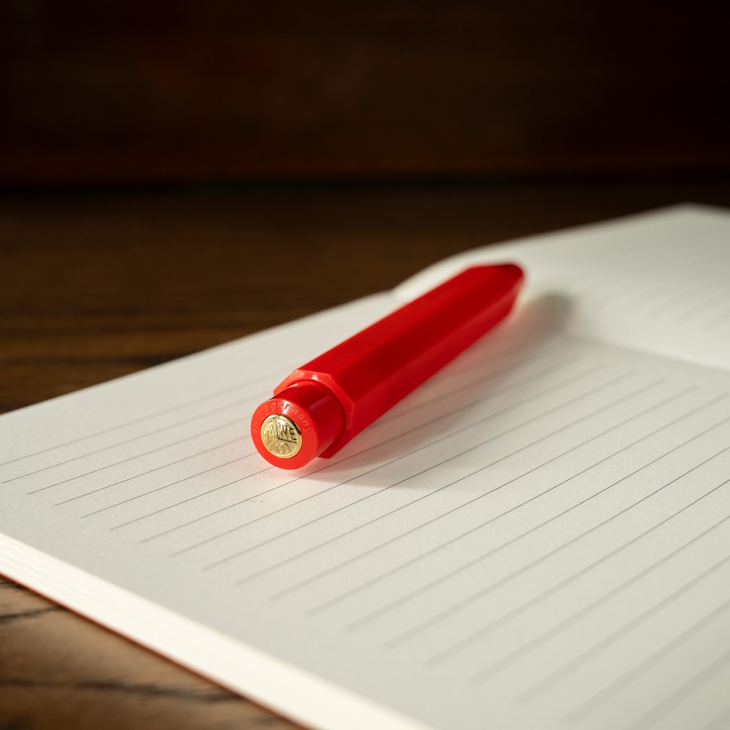 Kaweco Classic Sport red ballpoint pen push button barrel on a lined notebook