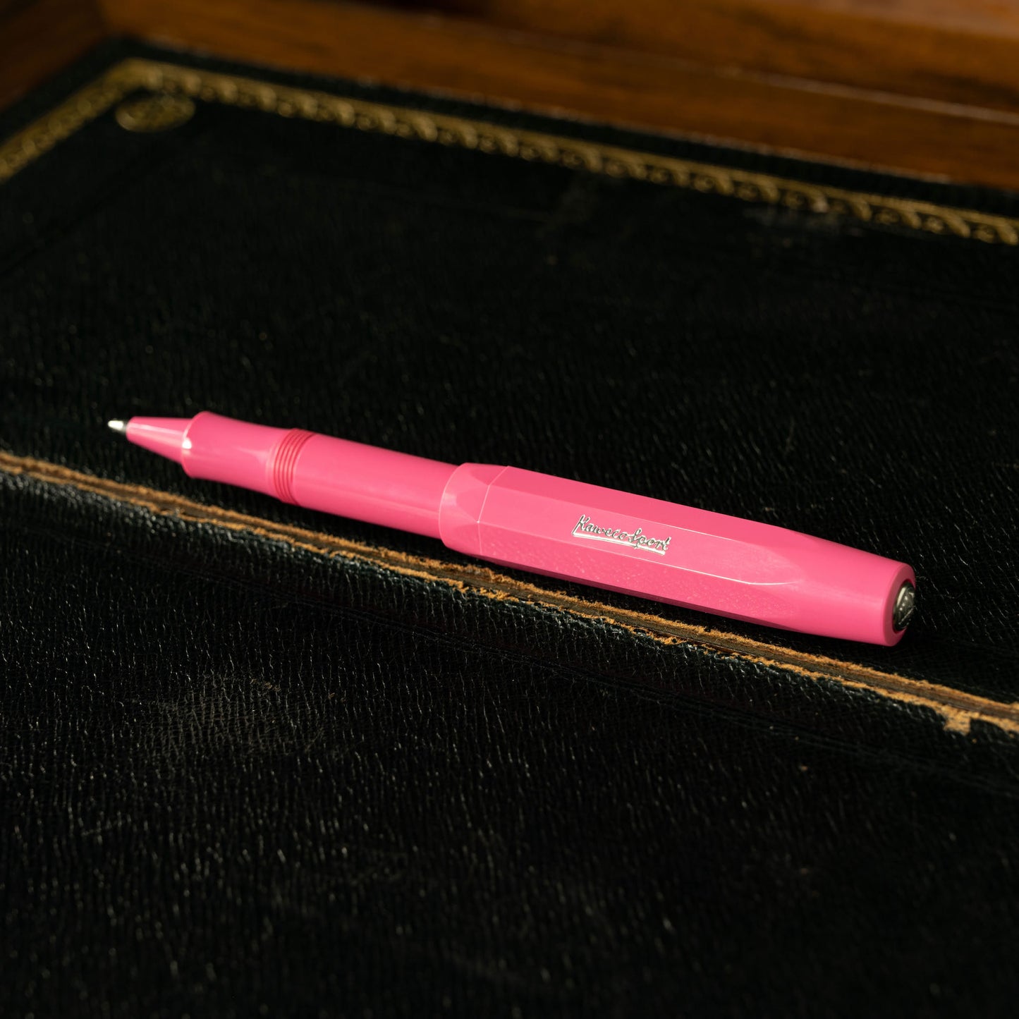 Kaweco Skyline Sport Pink Rollerball Pen with the lid attached to the barrel on a black textured surface