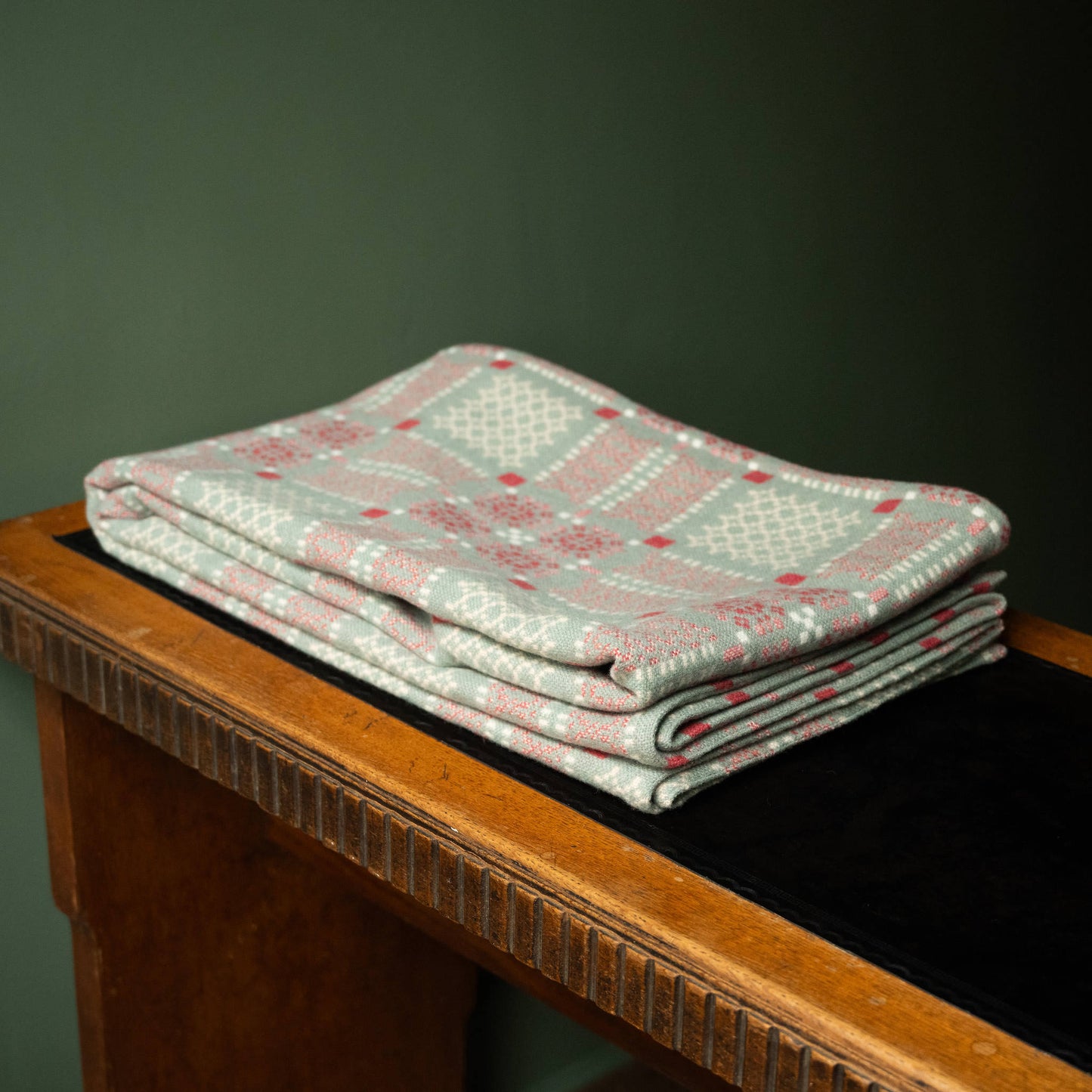 Melin Tregwynt Knot Garden Welsh Blanket in Rhiwob colourway folded on desk