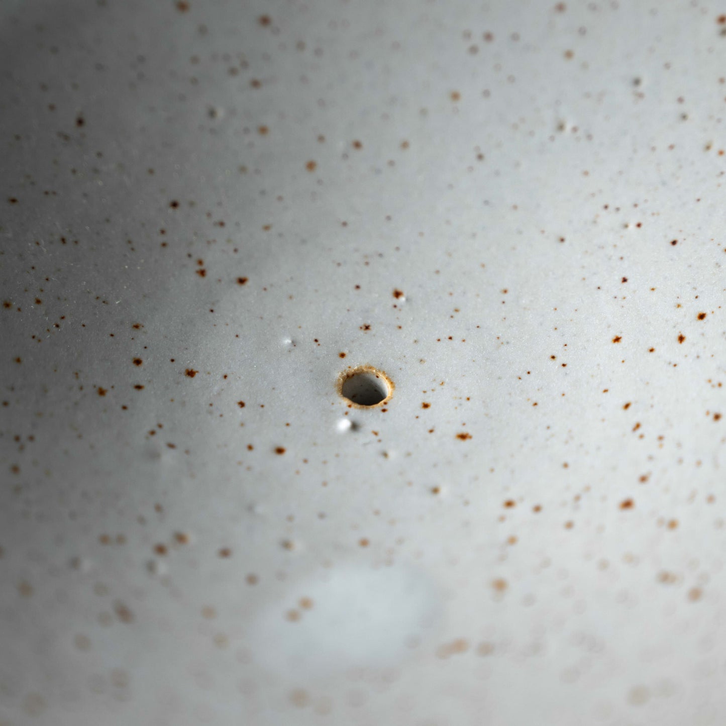 Pottery West speckled white stoneware soap dish close up of the drainage hole