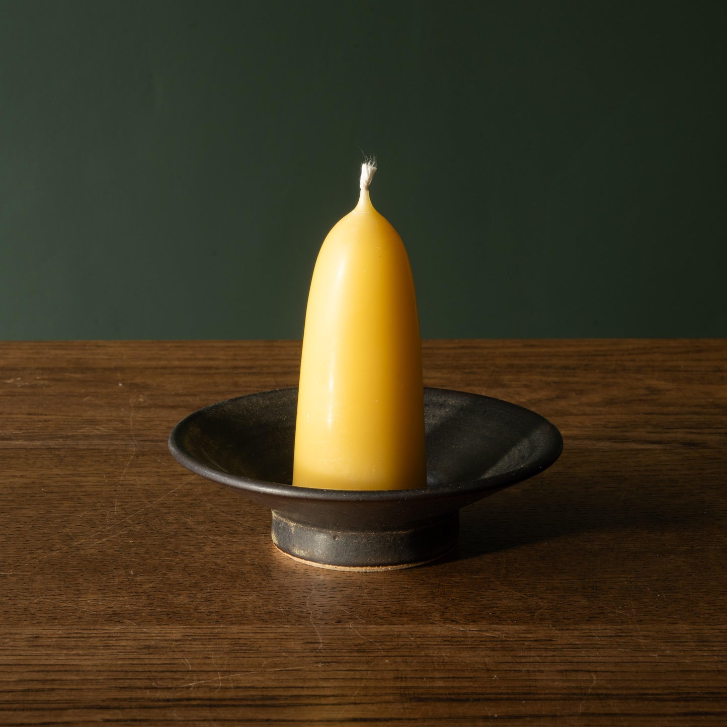 Pottery West stoneware stumpie candle holder in charcoal glaze with beeswax candle.