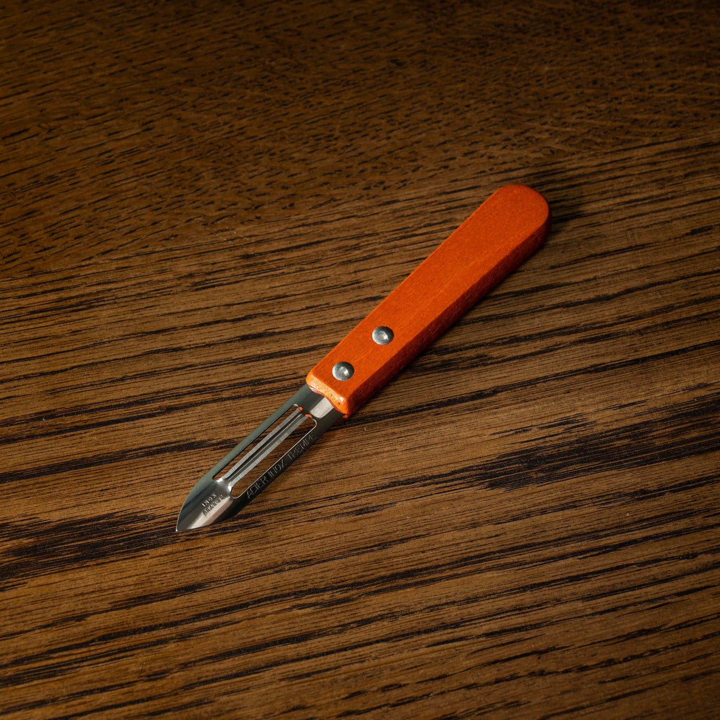 Vegetable peeler with orange stained wooden handle