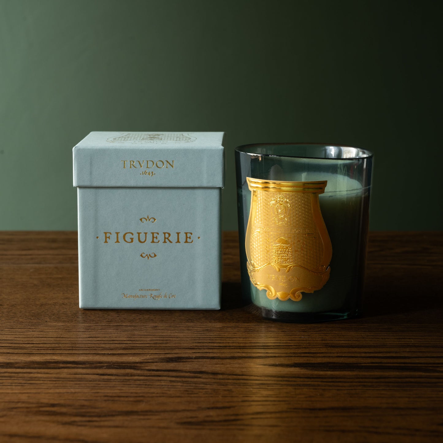 Trudon Figuerie Candle next to a branded box on a wooden surface.