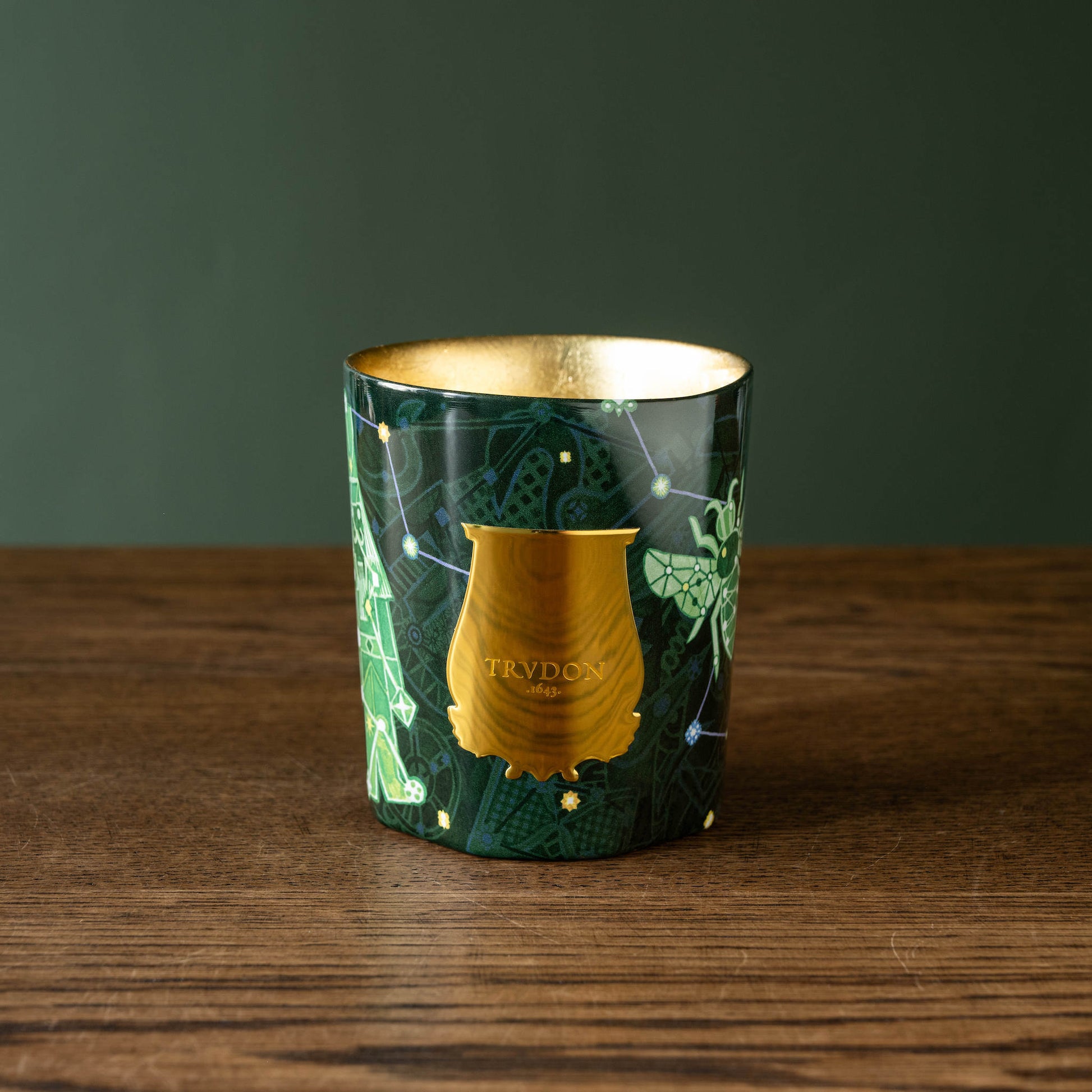 Trudon Enchanted Night Fir Candle in a decorative green and gold glass vessel