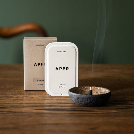 APFR Black Oud charcoal incense cone in a ceramic bowl with  packaging on a wooden surface