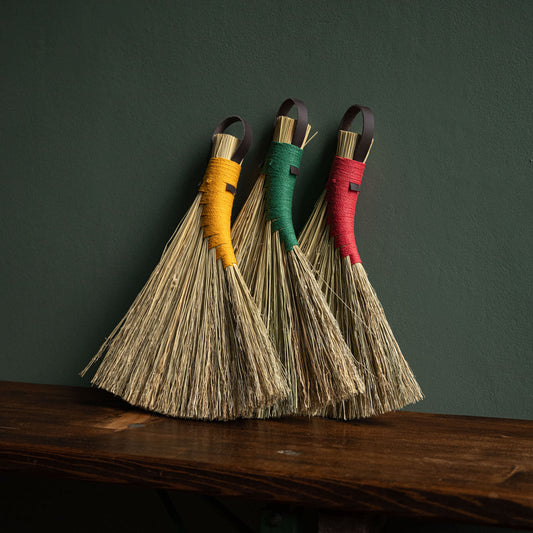 Three handmade Broomcorn hand brooms with hemp binding & dark brown leather hanging strap. Shown with choice of yellow, red or green hemp binding.  