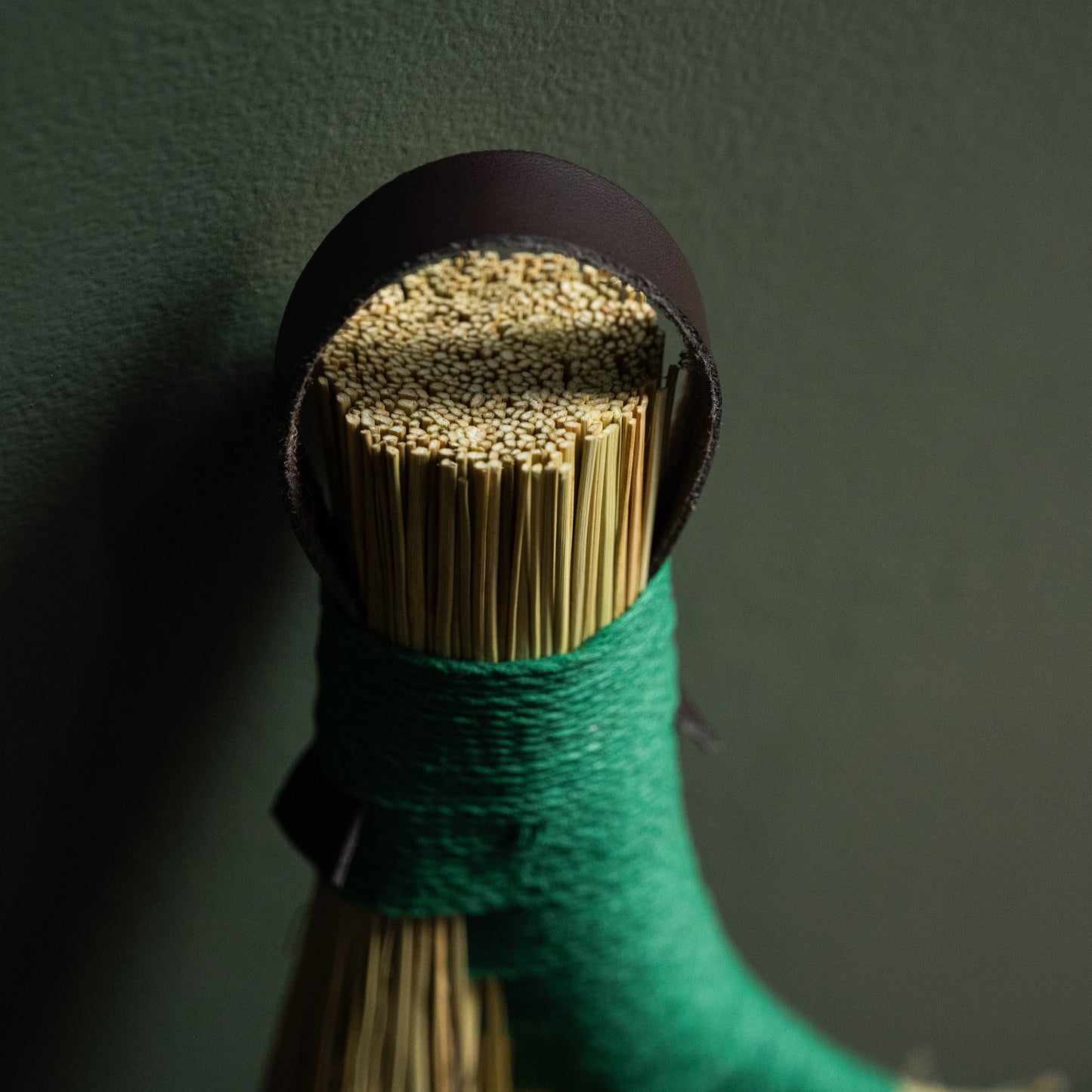 Close up of dark leather hanging strap & hemp binding for broomcorn hand broom. 