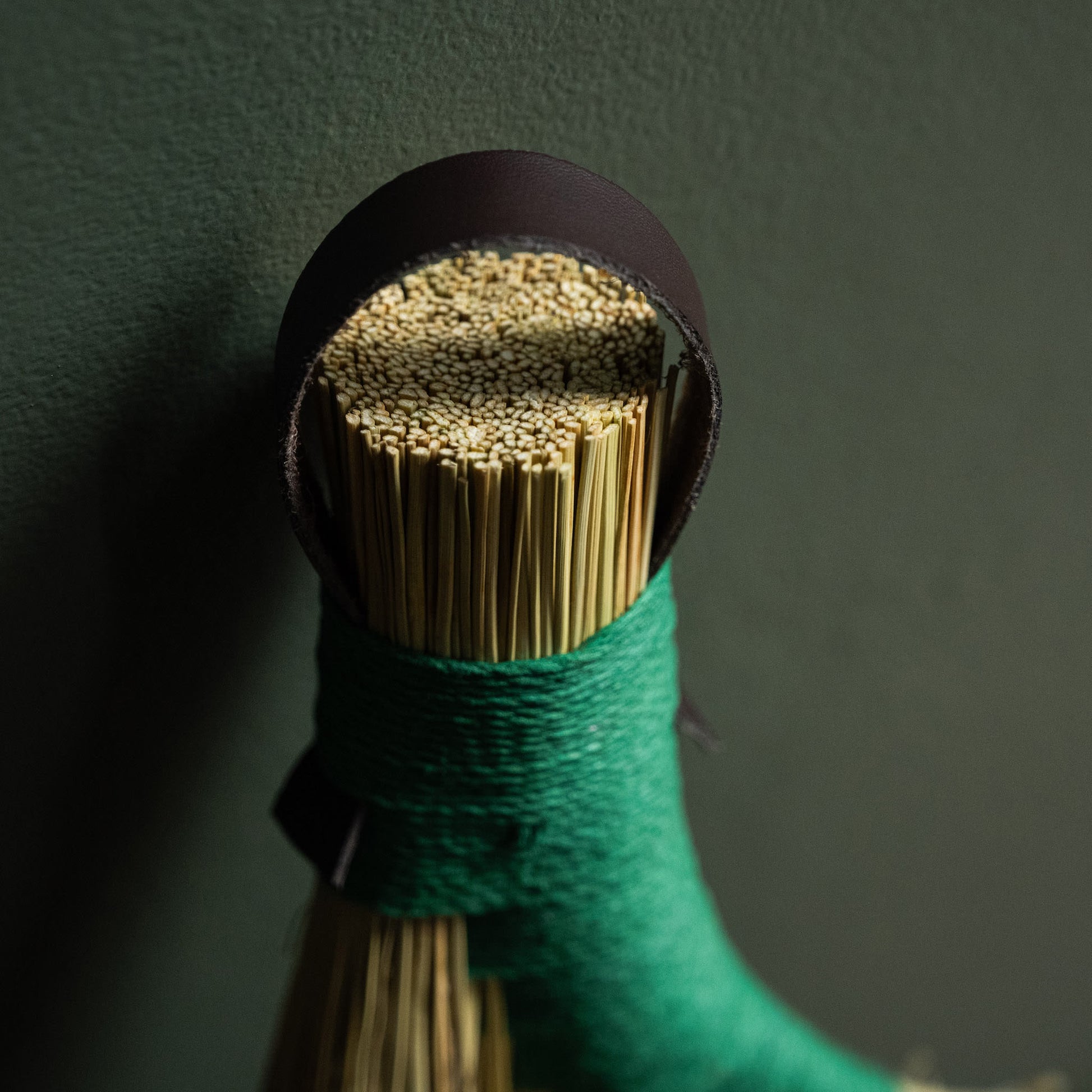 Close up of dark leather hanging strap & hemp binding for broomcorn hand broom. 