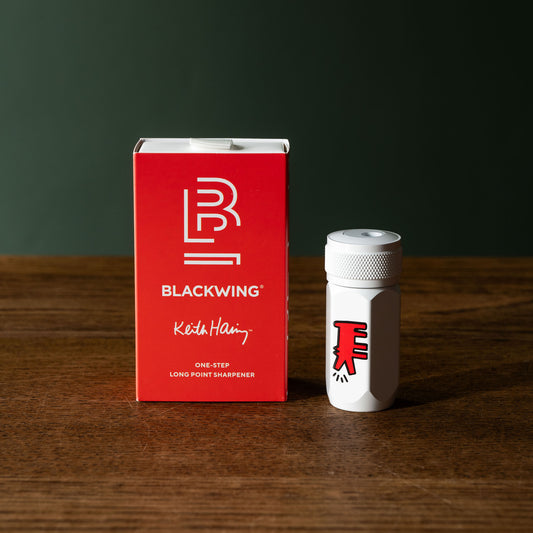 Blackwing Volume 292 Keith Haring "Dog" one-step long point sharpener with red packaging on a wooden surface