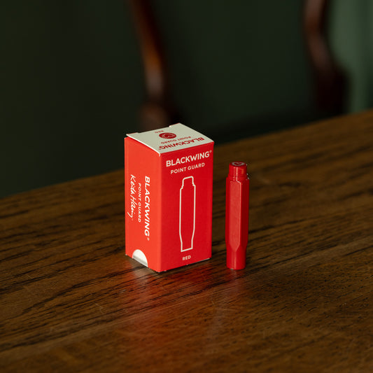 Blackwing Volume 292 Keith Haring red point guard & packaging on a wooden surface