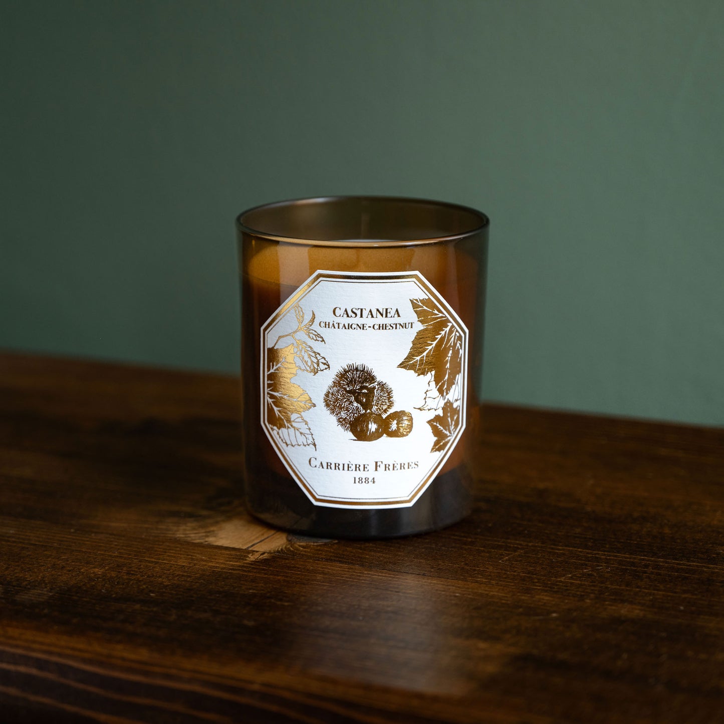 Carrière Frères Chestnut scented candle in an amber glass jar with a white and gold botanical label.