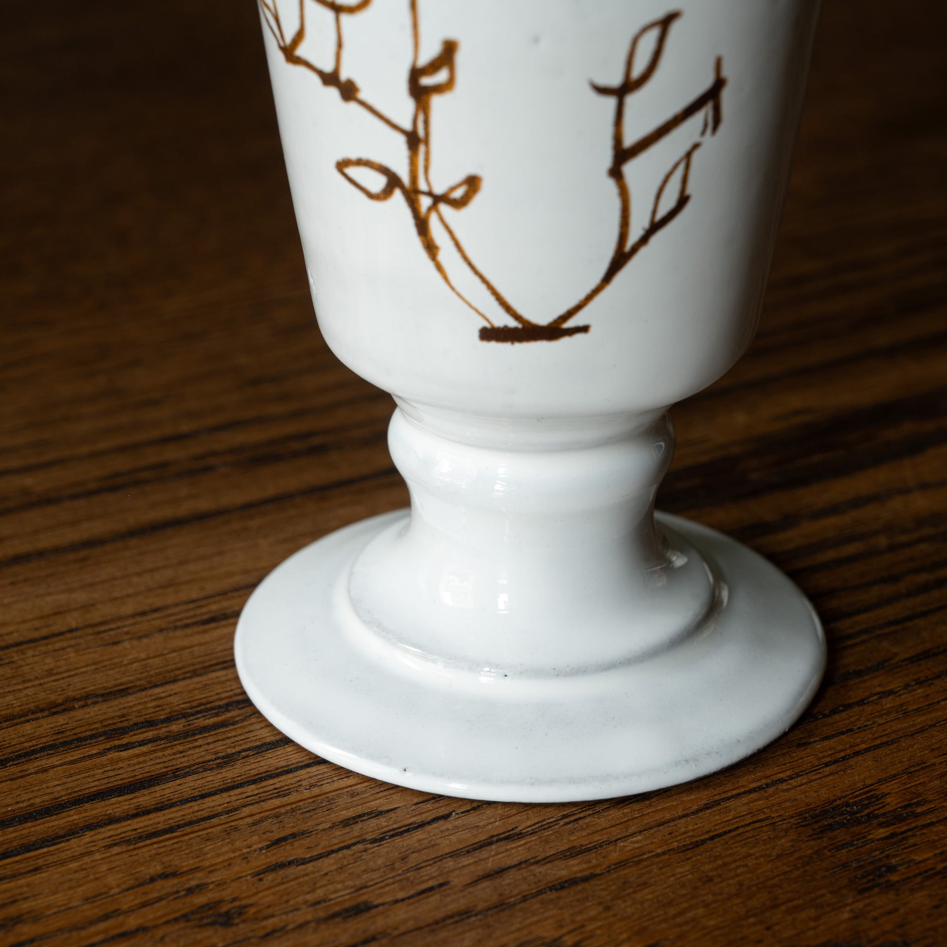 Base of Carron Paris white ceramic L'oiseau footed vase on a wooden surface