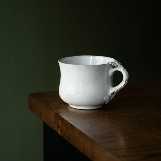 Carron Paris white ceramic Marie-Antoinette flared cup on a wooden surface with a dark background