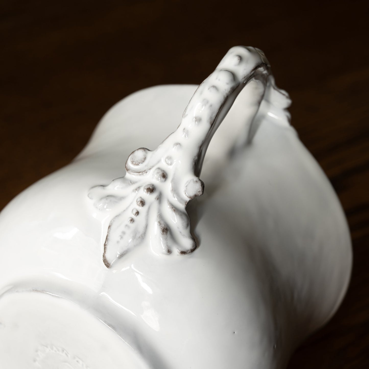 Close-up of a Carron Paris white ceramic Marie-Antoinette flared cup decorative handle on a dark background