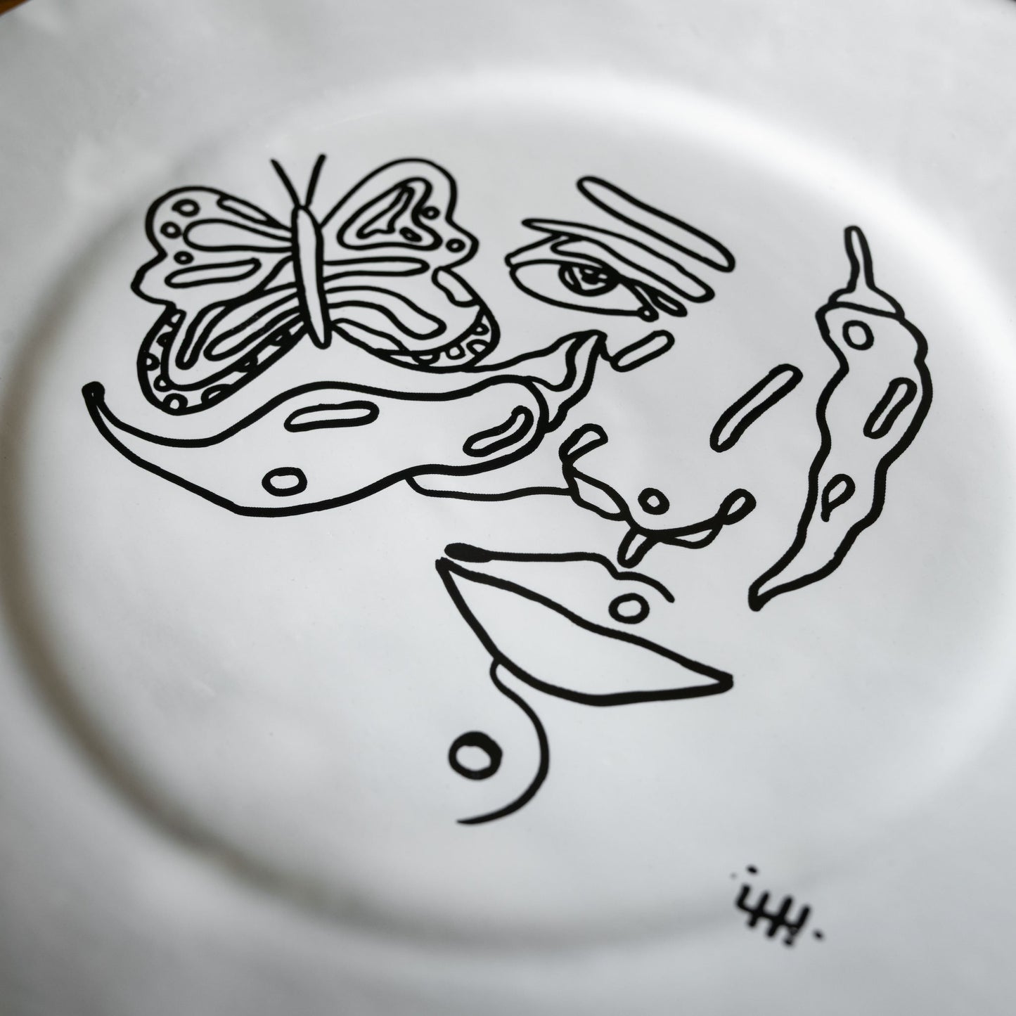 Carron Paris Piment et papillon large dessert plate showing close up detail of the abstract face illustration. 