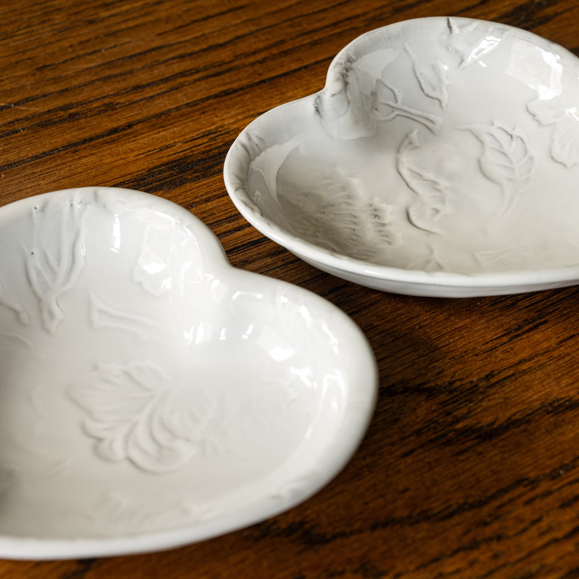 Top view of two Carron Paris Pivoine Heart Shaped Dishes with embossed peony flower design finished in a milky white glaze. 