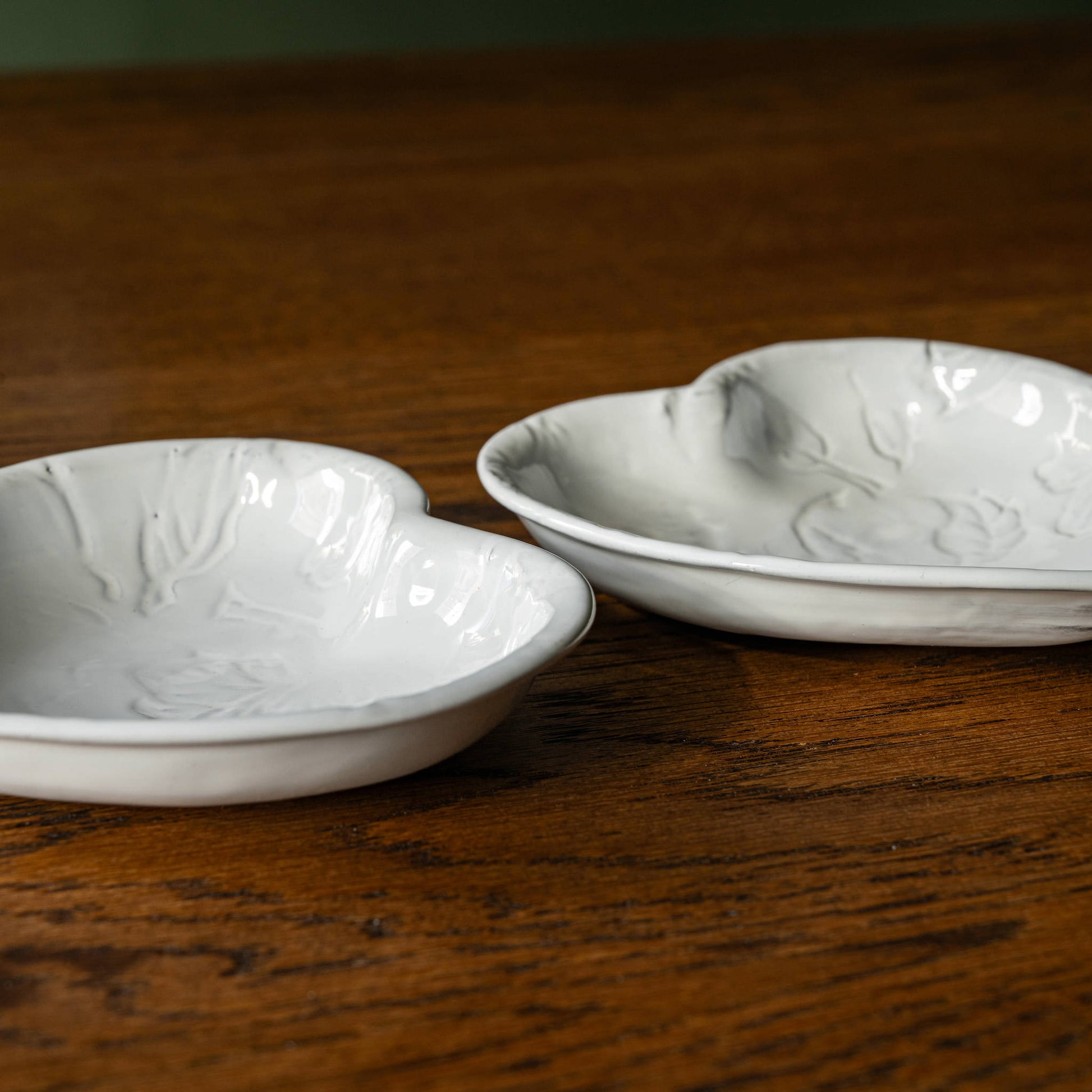 Side view of two Carron Paris Pivoine Heart Shaped Dishes with embossed peony flower design finished in a milky white glaze. 