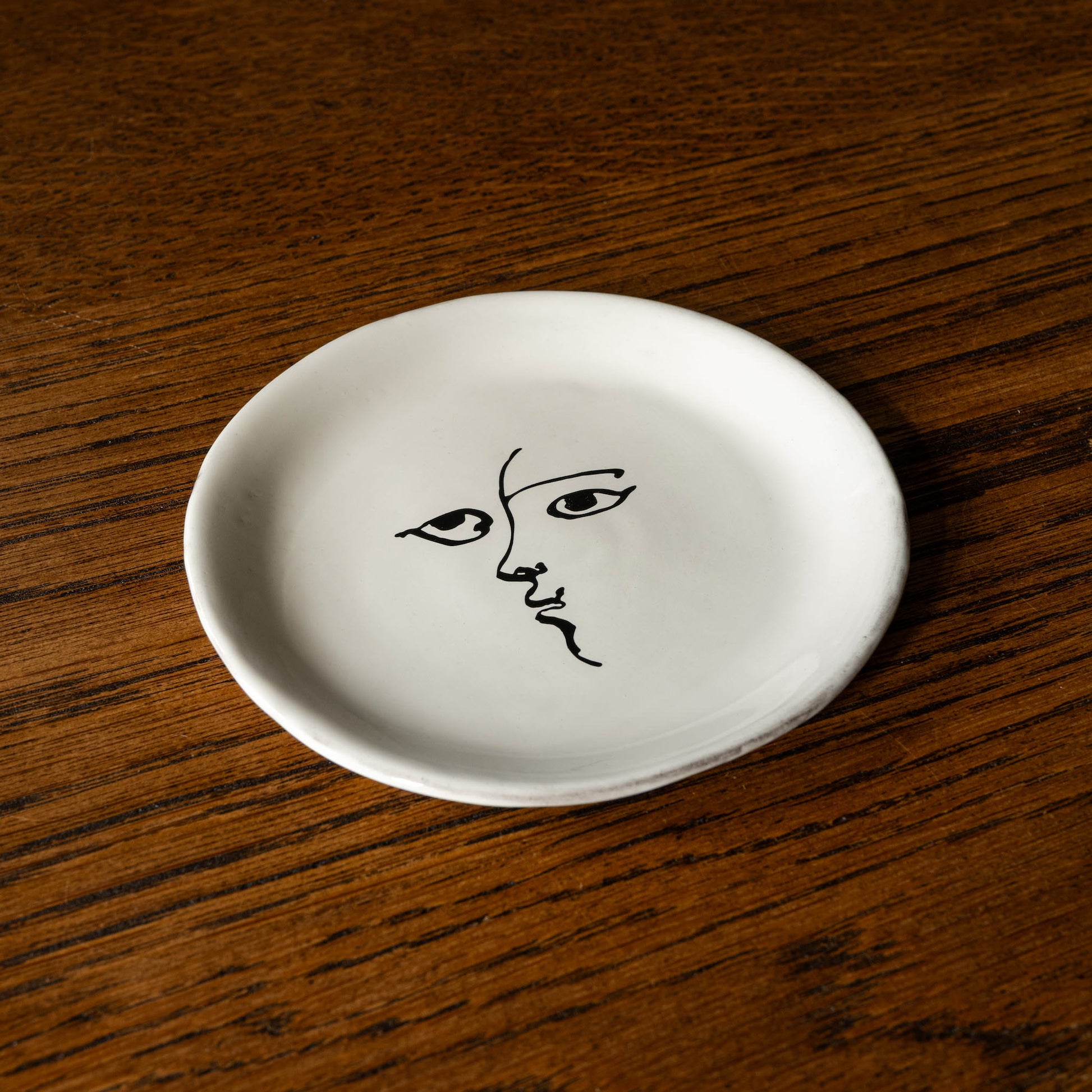 Carron Paris Toi et moi small plate in milky white glaze with an illustrated face design by Pierre Carron. 