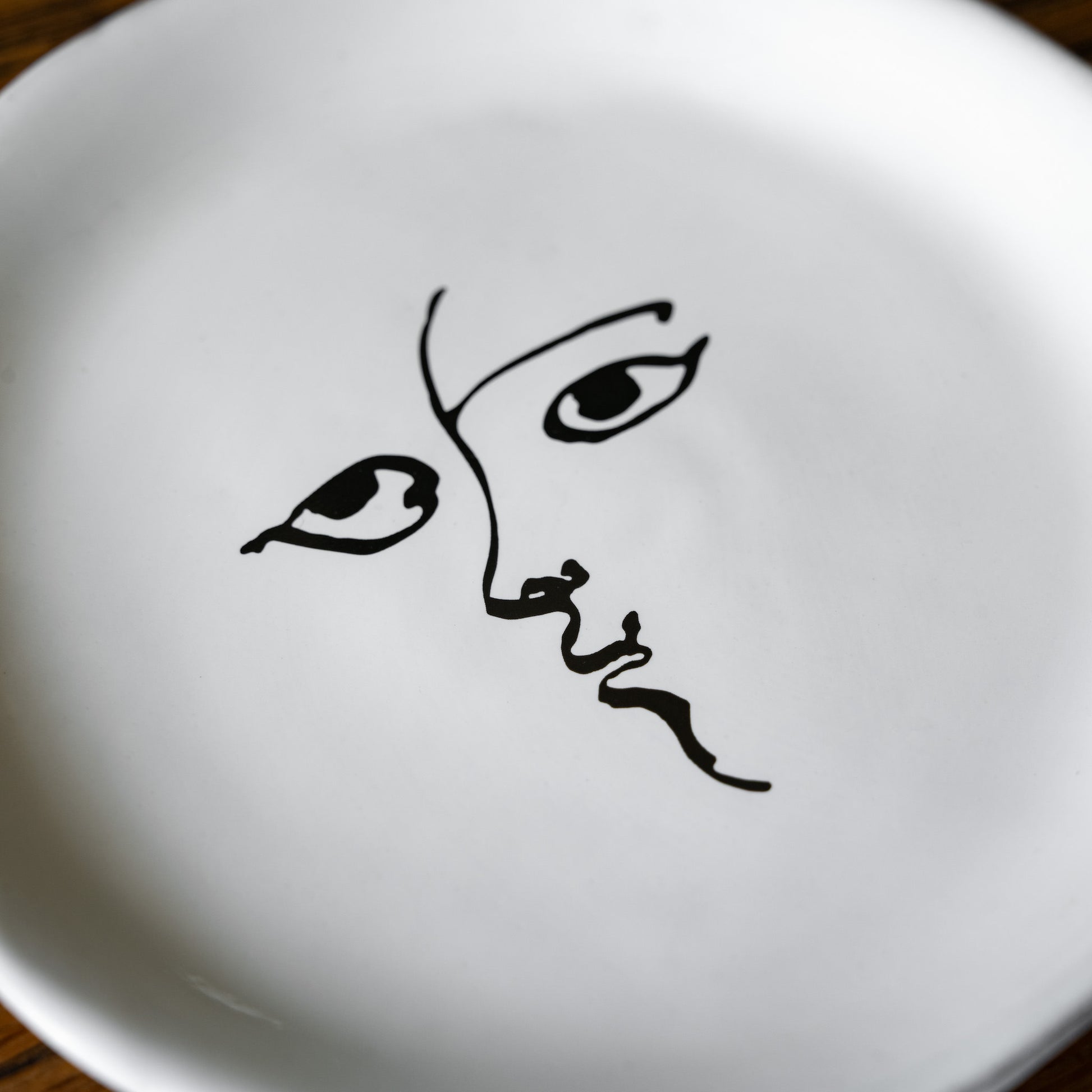 Close up of illustrated face design of the Carron Paris Toi et moi small plate. 