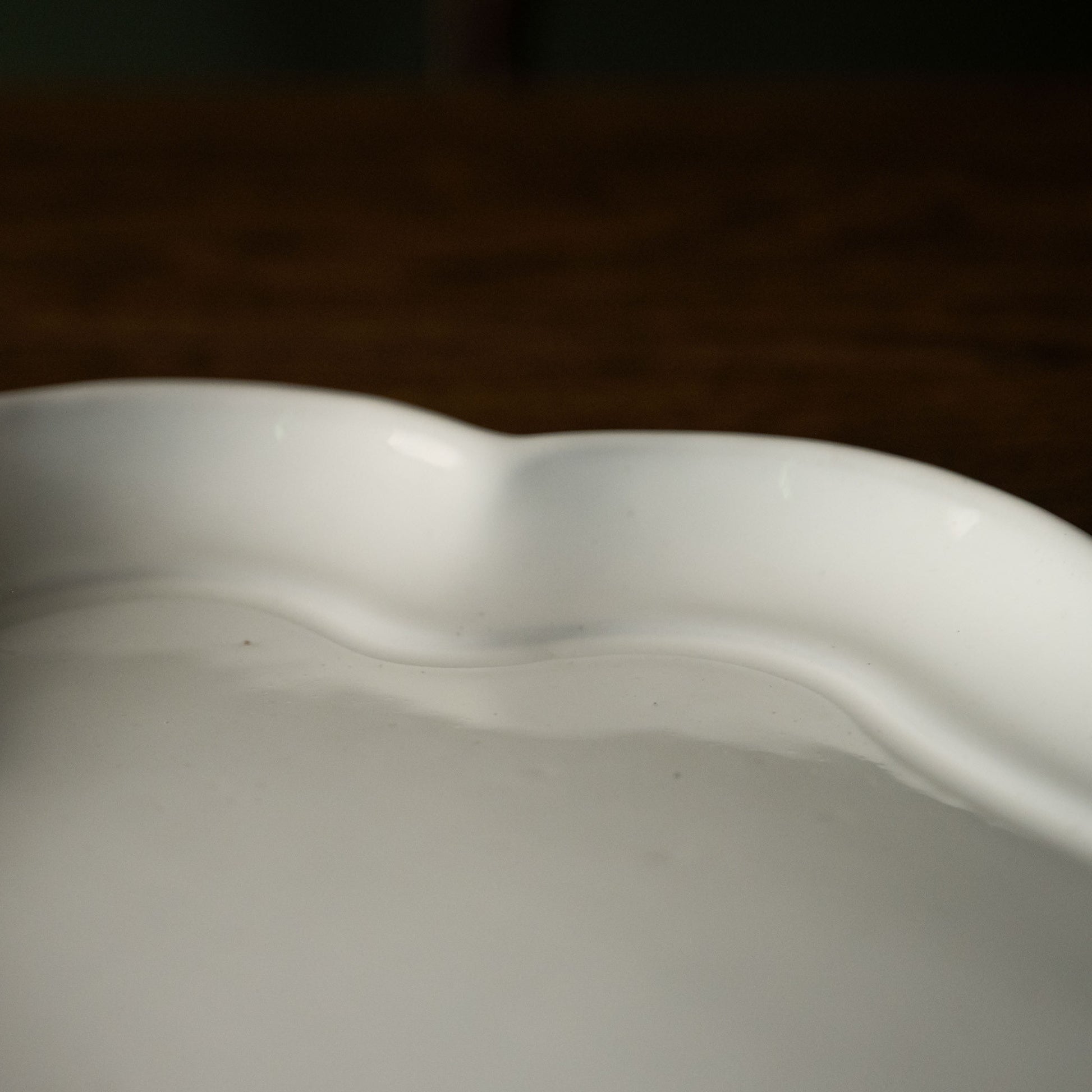 Close-up of a Carron Paris white ceramic platter with wavy edge 