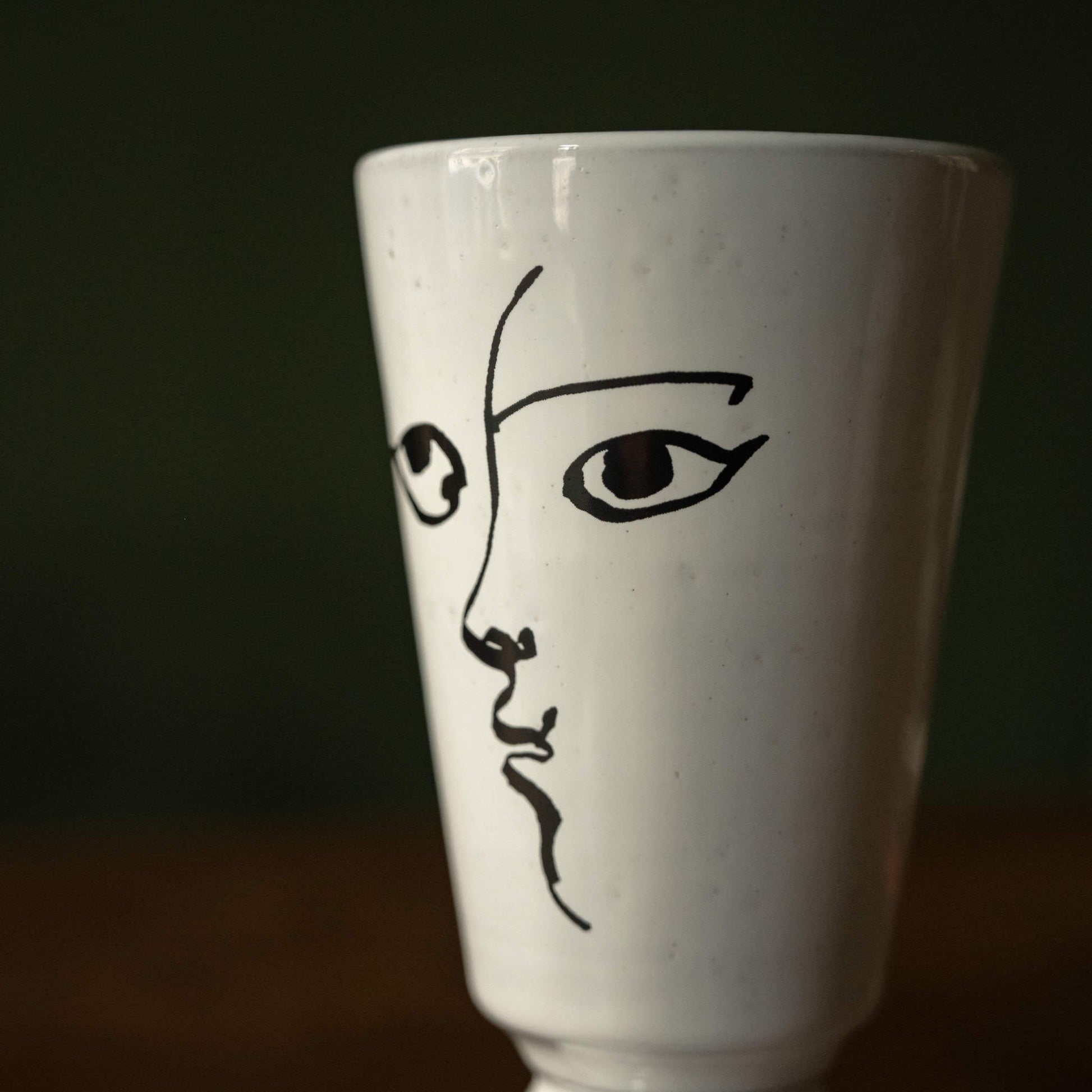 Close-up of Carron Paris small white ceramic vase with black line art of a face 