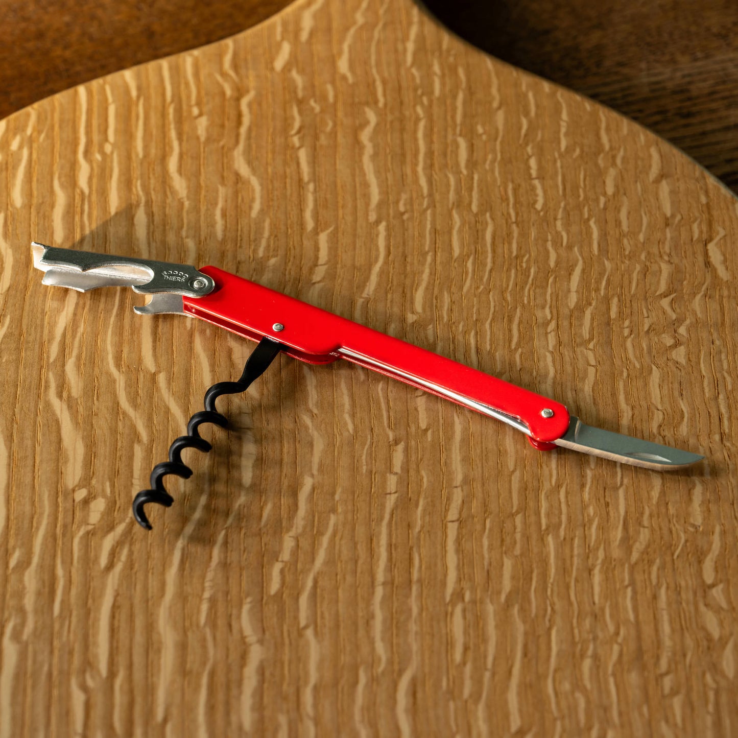 Red Cartailler Deluc corkscrew on a wooden serving board
