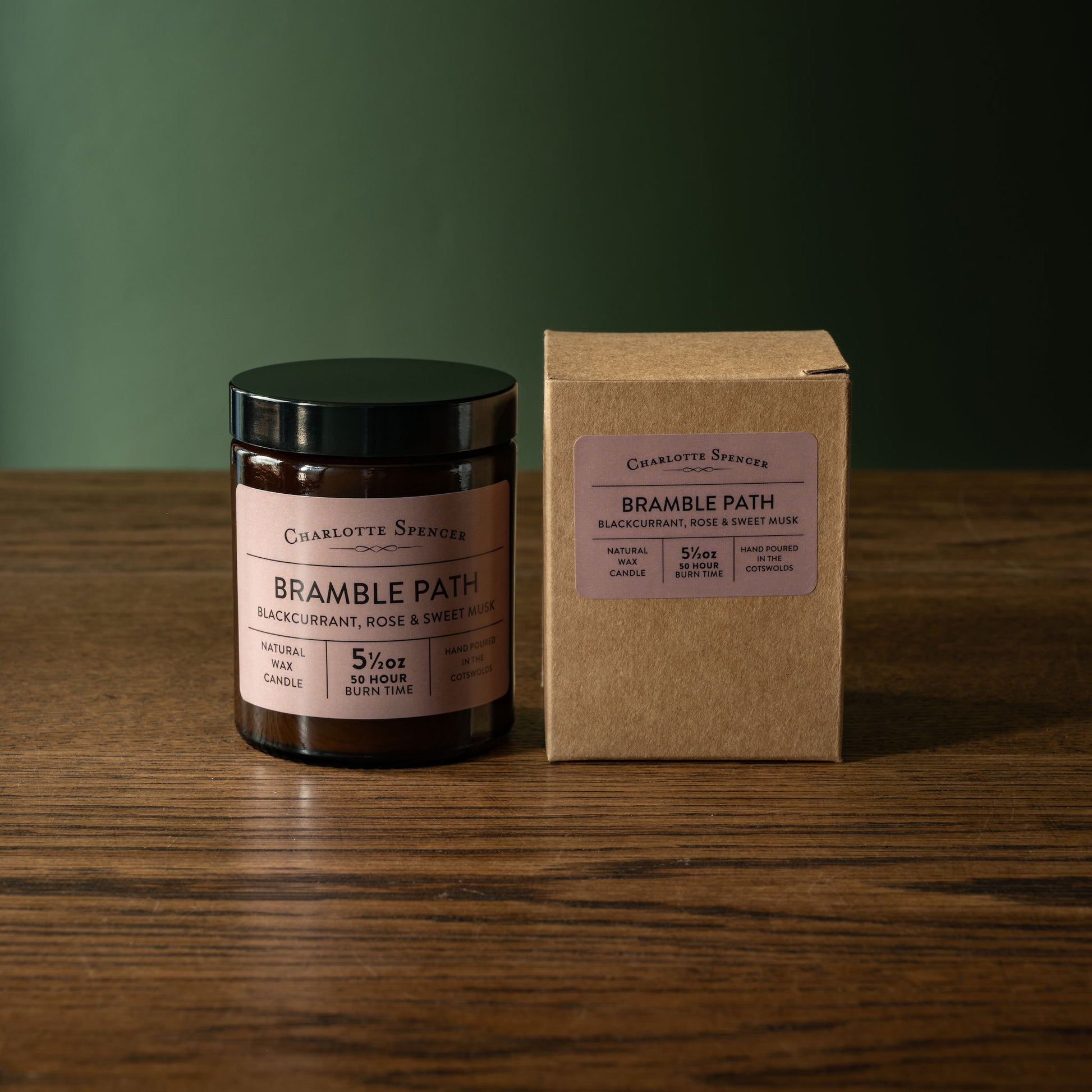 Charlotte Spencer "Bramble Path" candle and box on a wooden surface with a green background