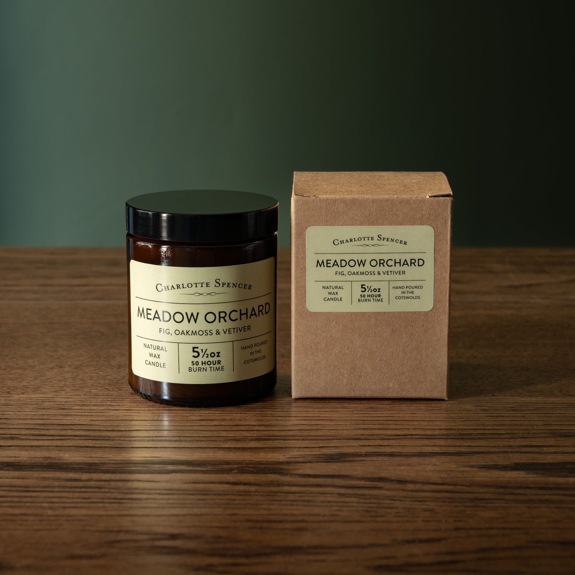 Charlotte Spencer 'Meadow Orchard' candle and recycled card box on a wooden surface with a green background