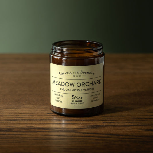 Charlotte Spencer 'Meadow Orchard' candle on a wooden surface with a dark background
