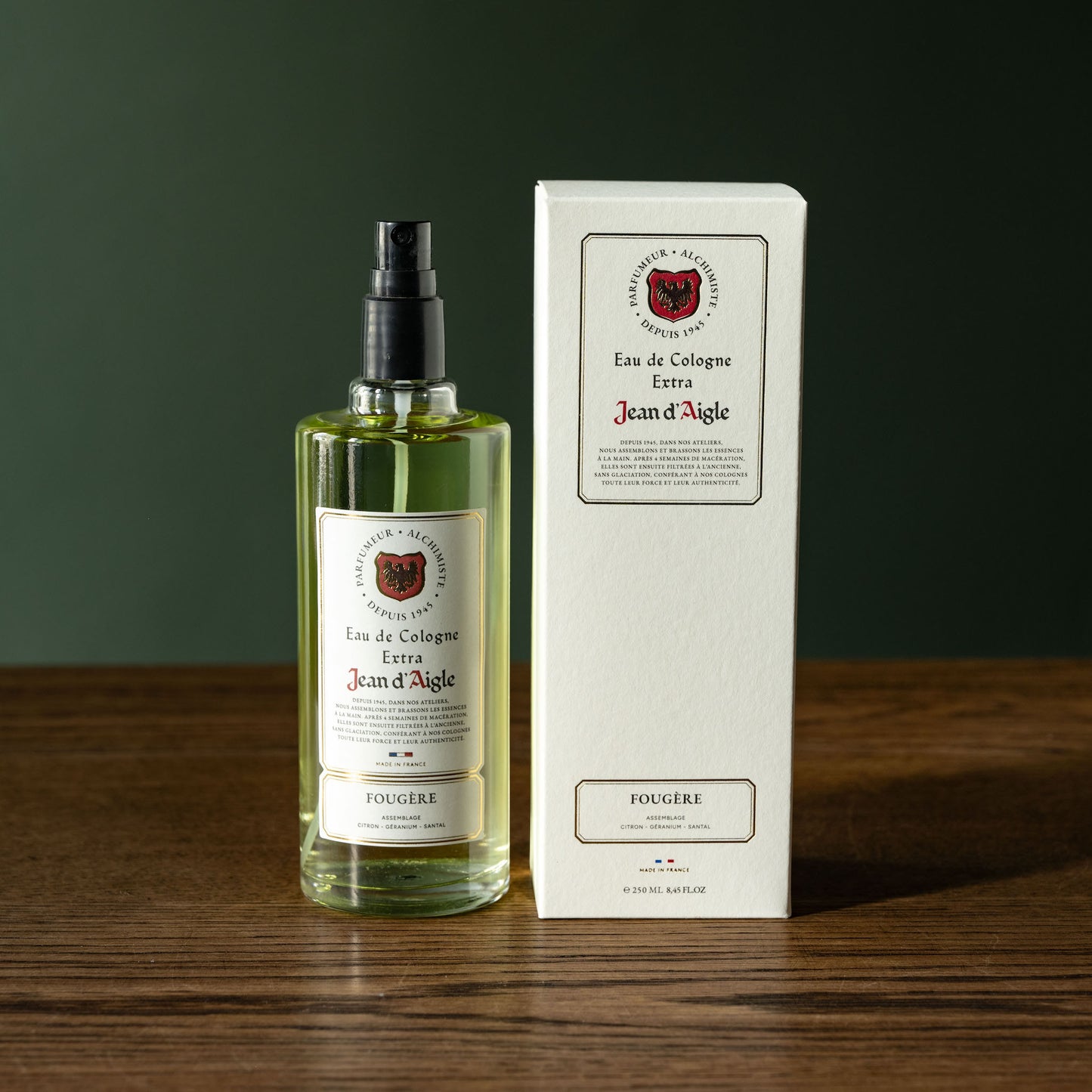 Bottle and box of Jean d'Aigle fougere Eau de Cologne on a wooden surface with a dark background