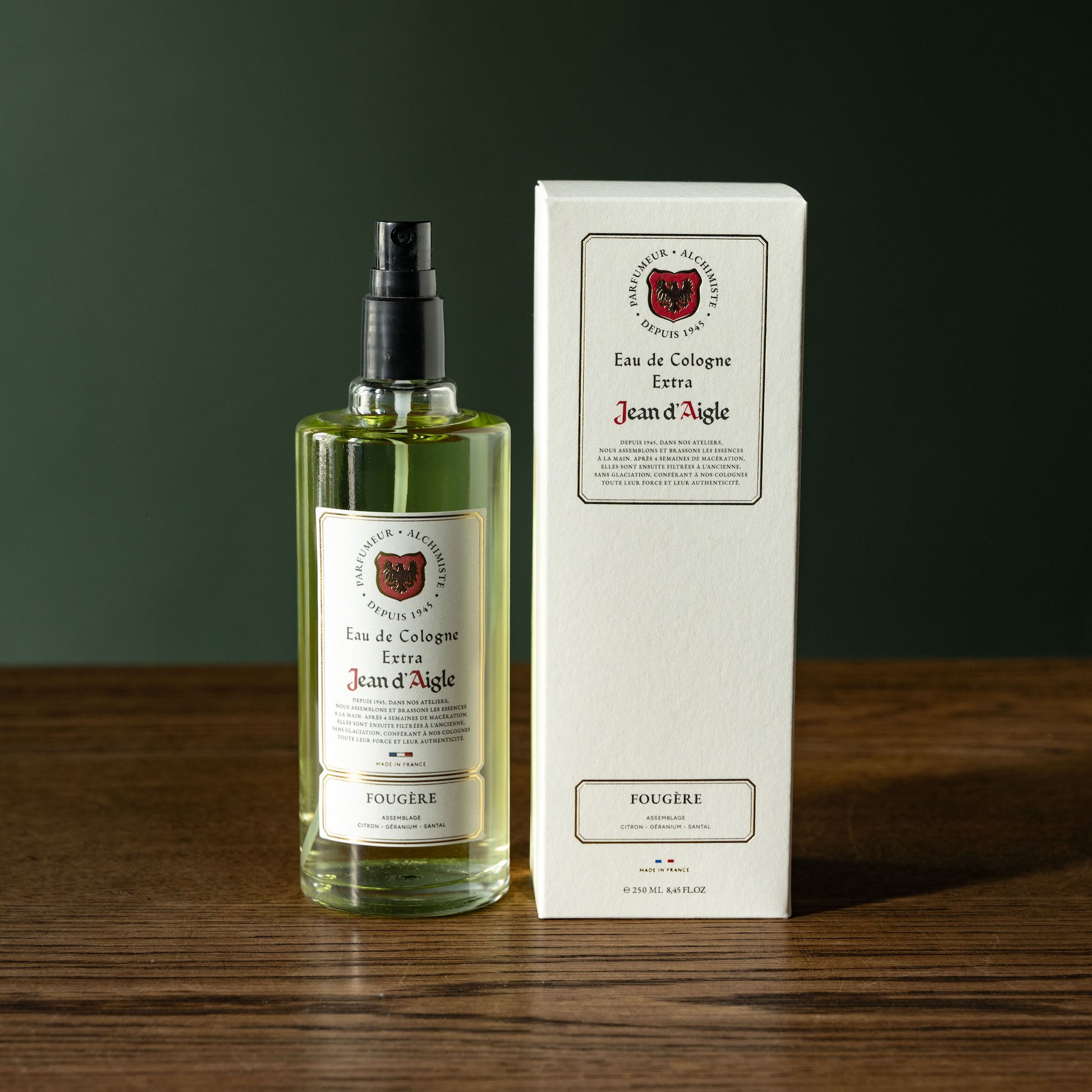 Bottle and box of Jean d'Aigle fougere Eau de Cologne on a wooden surface with a dark background