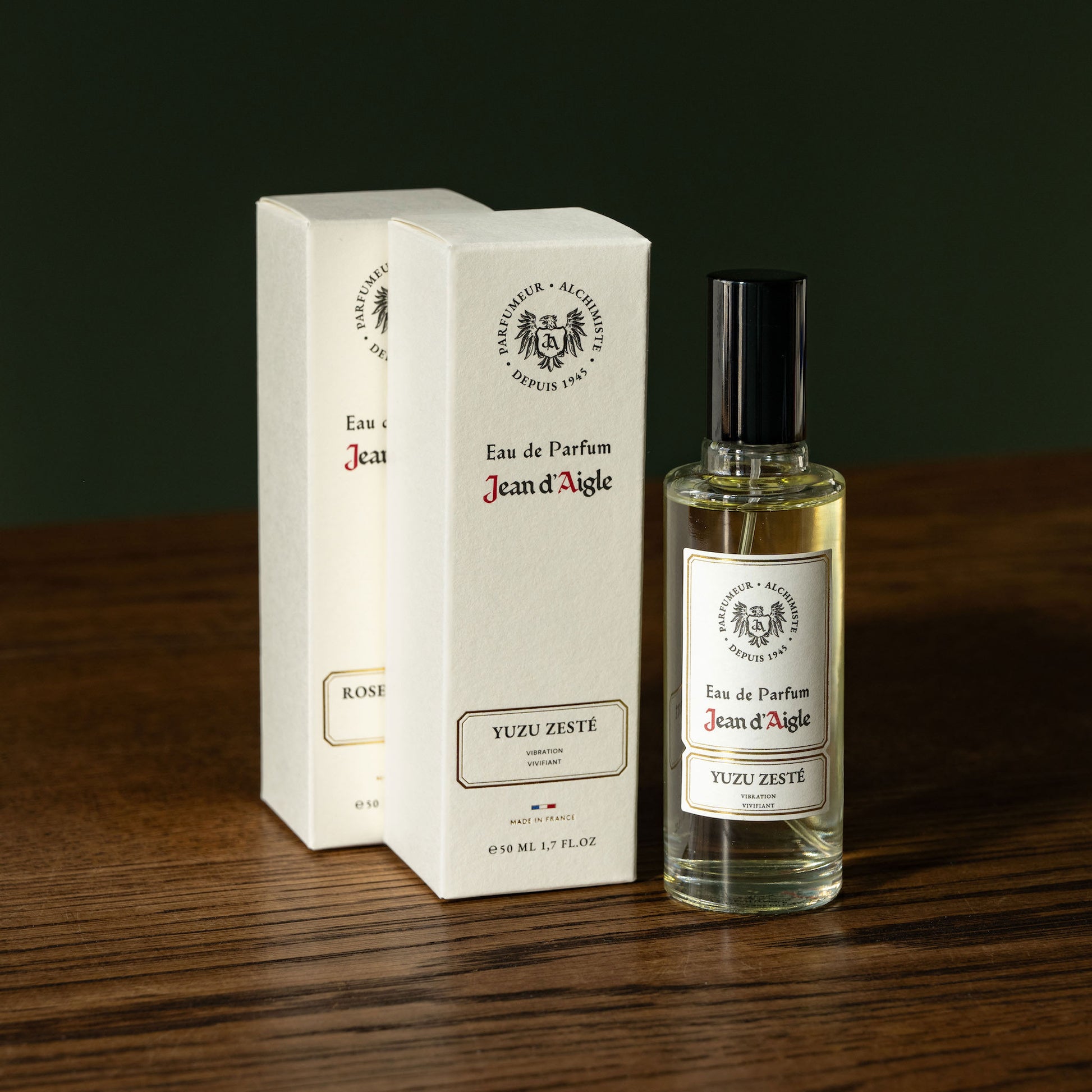 Jean d'Aigle Eau de Parfum bottle and packaging on a wooden surface with a dark background