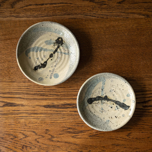 Two Joshua Williams earthenware plates with unique slip designs on a cream base glaze