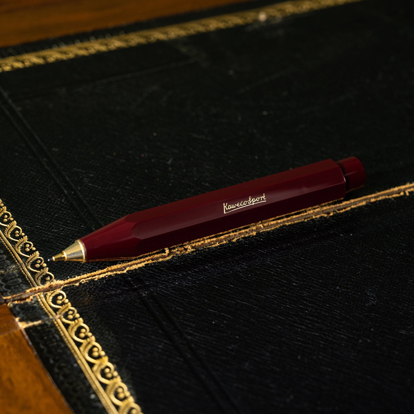 Kaweco Classic Sport Bordeaux pencil with gold accents on an antique writing desk 