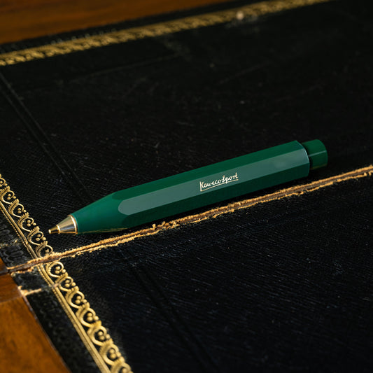 Kaweco Classic Sport green mechanical pencil with gold accents on a black leather surface