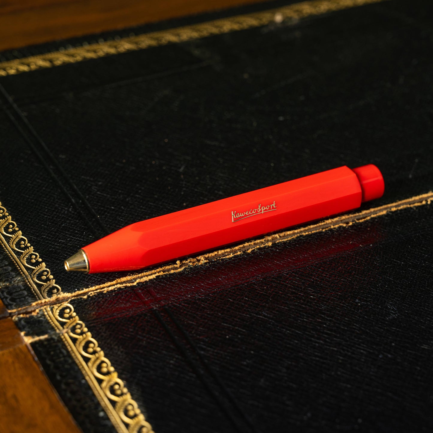 Kaweco Classic Sport red ballpoint pen on a black leather surface