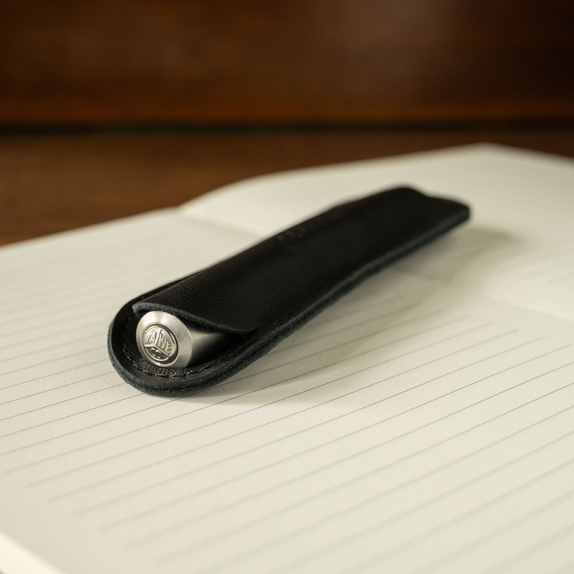 Kaweco black leather pen pouch with silver pen inside on a lined notebook page